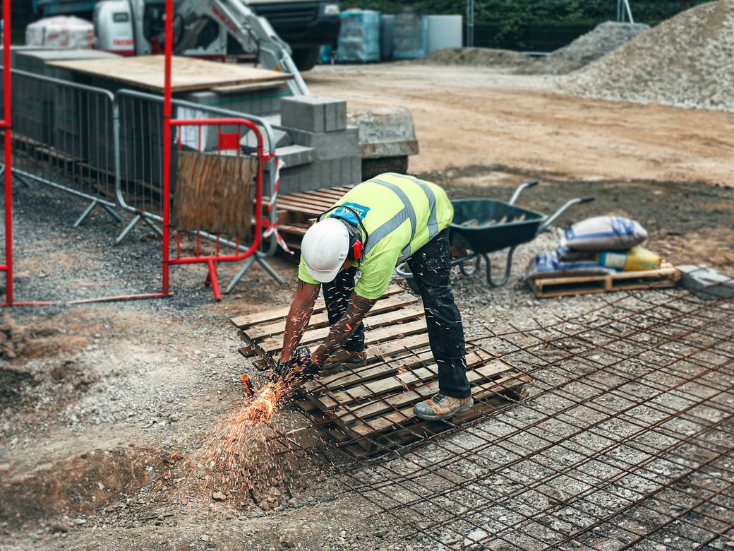 A worker in a high visibility vest cutting steel reinforcement on a building site